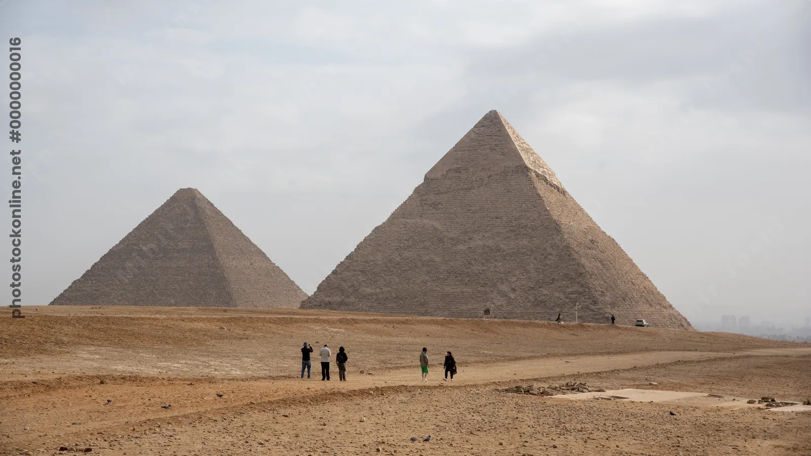 Tourists seen taking photos of the Great Pyramids of Giza from the desert in Egypt - an iconic archaeological and travel destination.