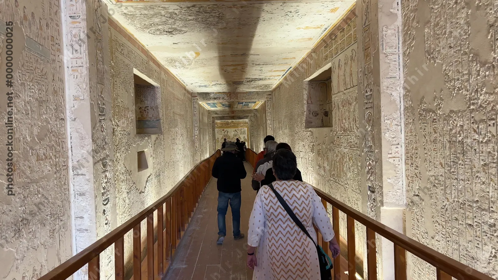 Tourists walking inside decorated tomb passage in the Valley of the Kings