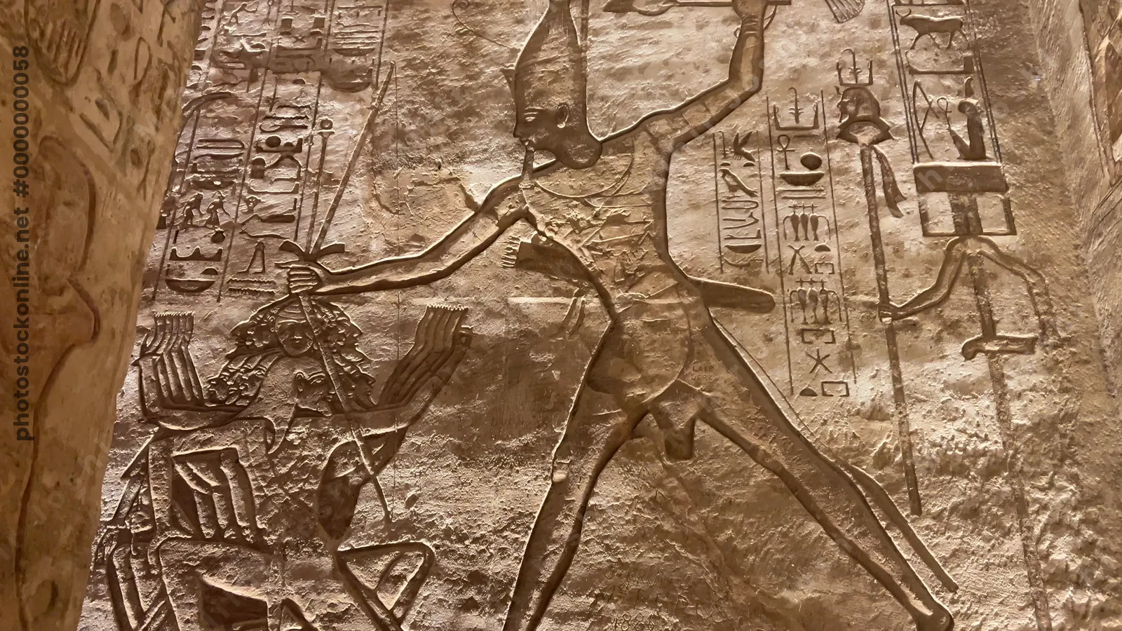 Ancient relief at Abu Simbel showing Pharaoh smiting enemies with hieroglyphs.