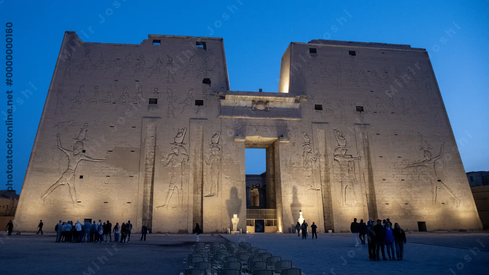 Temple of Edfu illuminated at dawn - golden lights highlight the ancient structure as the sky transitions from night to day in Edfu, Egypt.