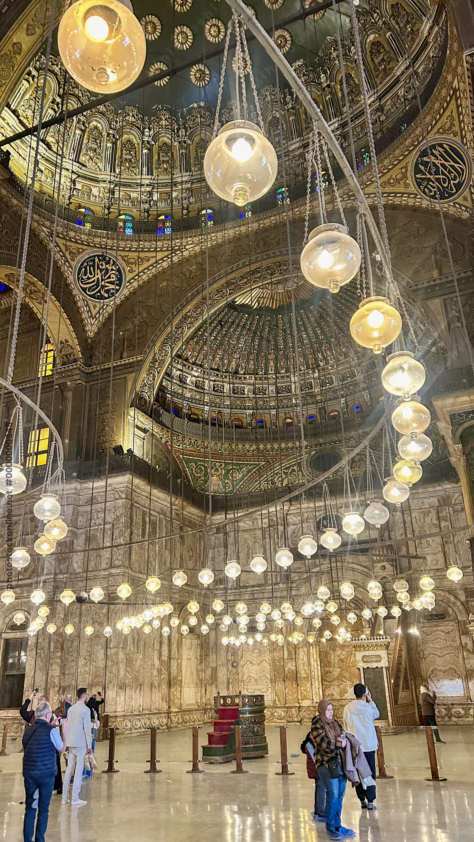 Cairo, Egypt - Feb 6, 2025: People admiring the interior of the Muhammad Ali mosque (or Alabaster mosque) with its beautiful lighting and chandelier in the citadel of Cairo, Egypt