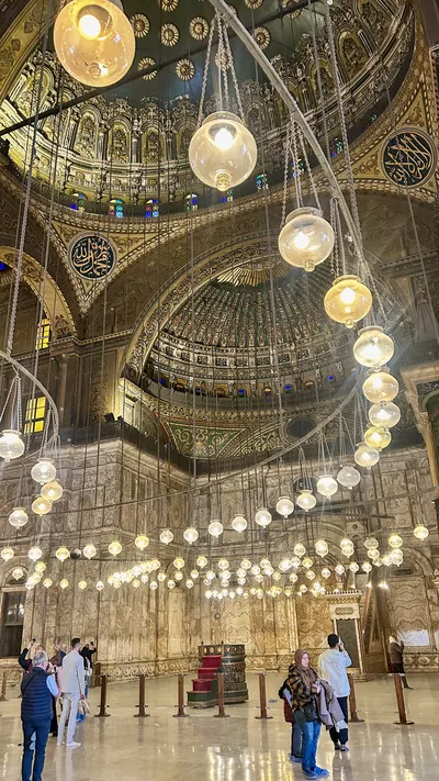 Cairo, Egypt - Feb 6, 2025: People admiring the interior of the Muhammad Ali mosque (or Alabaster mosque) with its beautiful lighting and chandelier in the citadel of Cairo, Egypt
