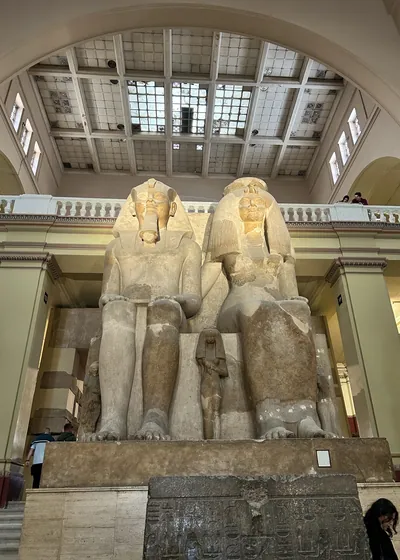 Cairo, Egypt - Feb 4, 2025: Massive seated statue of Pharaoh Amenhotep III with Queen Tiye and daughters, symbolizing royal power and family, displayed at the Egyptian Museum in Cairo.