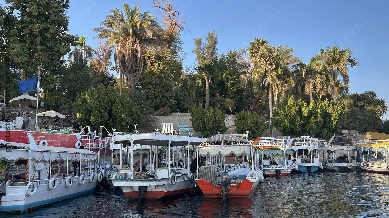 Aswan, Egypt - Feb 7, 2025: Small boats docked along the Nile near the Aswan Botanical Garden in Aswan, Egypt