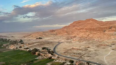 Luxor, Egypt - Feb 10, 2024:Scenic aerial view of ancient ruins, green fields, and desert mountains near Luxor, Egypt, taken during a hot air balloon ride.