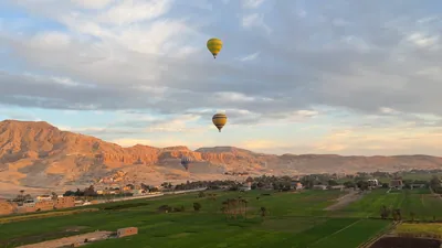 Hot air balloons over Luxor at sunrise with deser