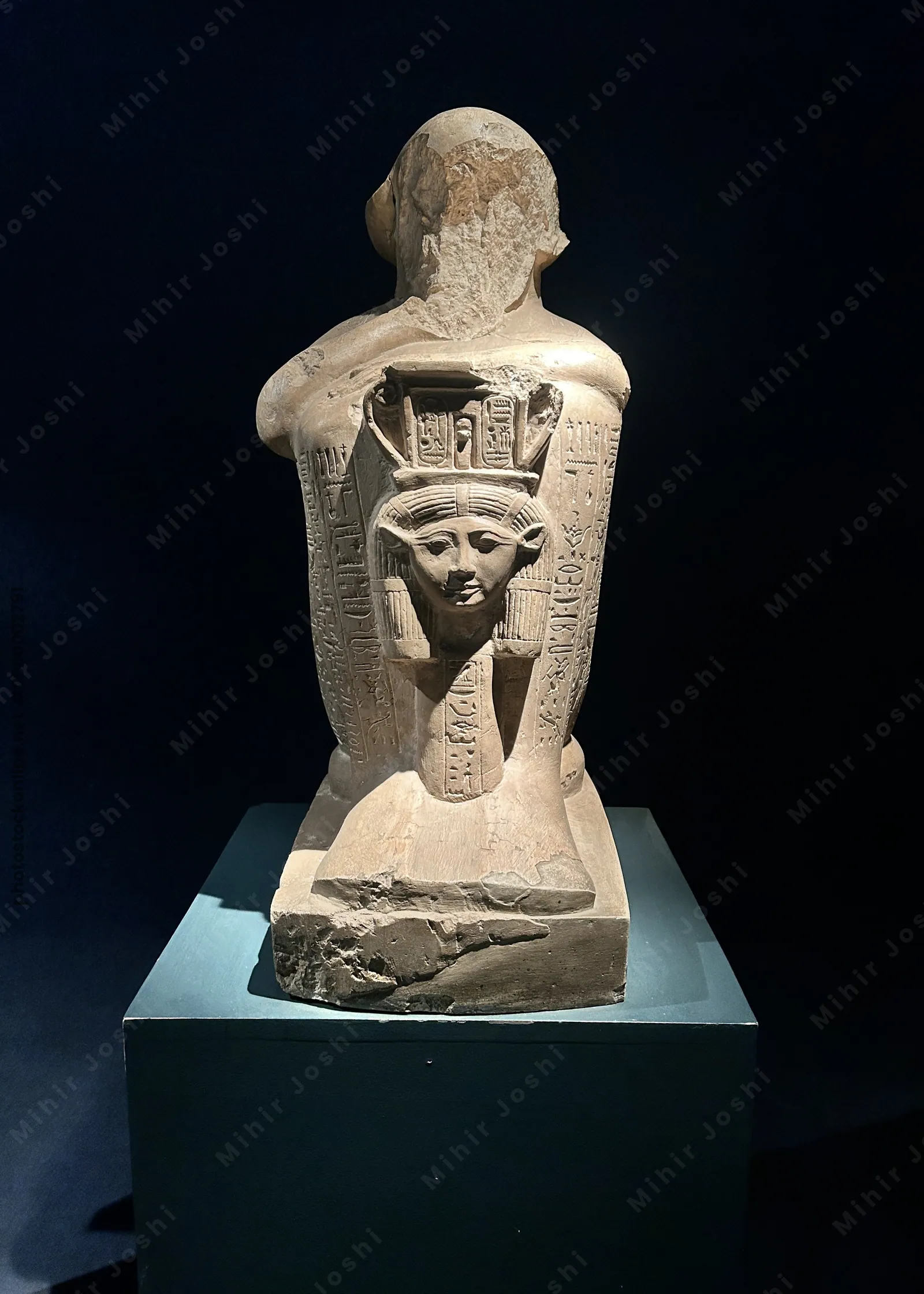 Luxor, Egypt - Feb 9, 2025: Statue fragment with hieroglyphic inscriptions and a carved goddess figure on the back, displayed in Luxor Museum.