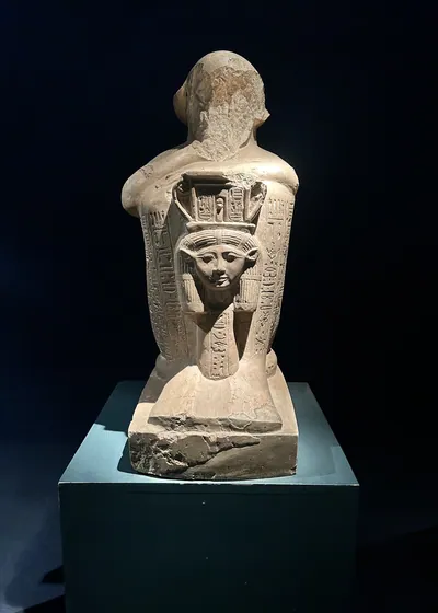 Luxor, Egypt - Feb 9, 2025: Statue fragment with hieroglyphic inscriptions and a carved goddess figure on the back, displayed in Luxor Museum.