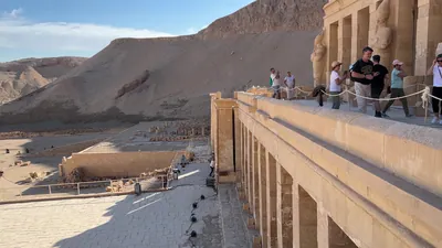 Luxor, Egypt - Feb 12, 2025: Tourists on the middle terrace of the Mortuary Temple of Queen Hatshepsut at Deir el-Bahari, showing temple architecture and surrounding cliffs.