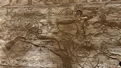 Aswan, Egypt - Feb 8, 2025: Ancient battle relief at Abu Simbel showing Pharaoh Ramesses II in a chariot with bow, part of the Battle of Kadesh scenes