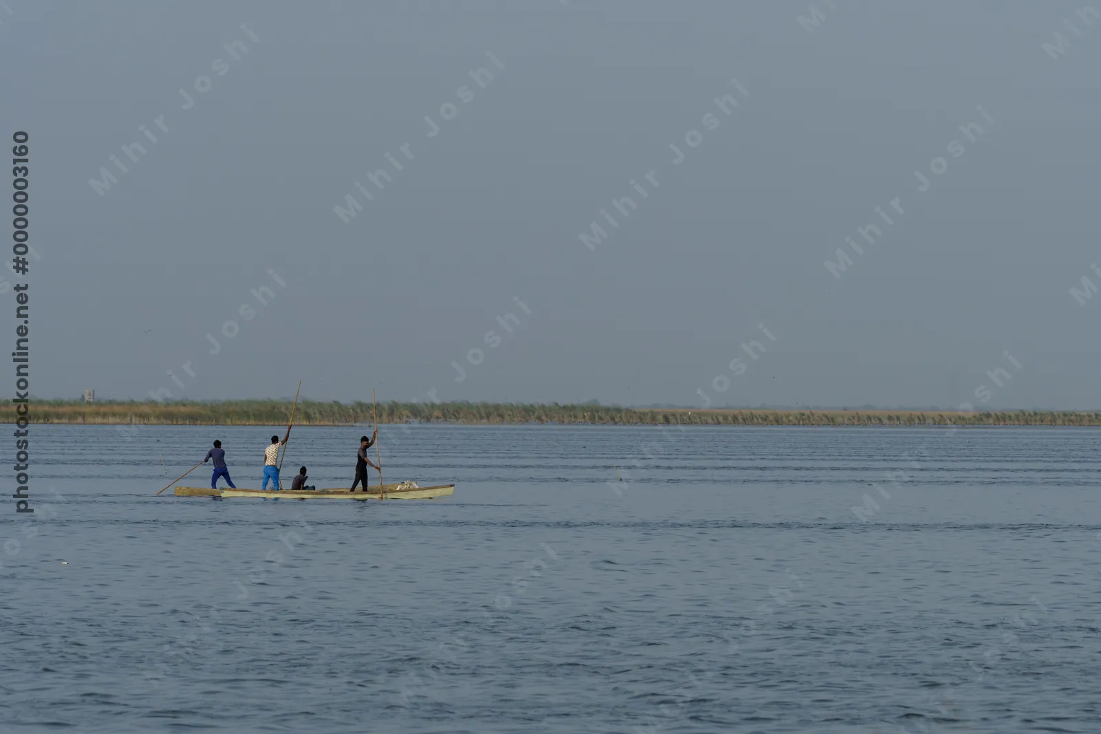 Nalsarovar, Gujarat, India - June 12, 2025: Fishermen rowing a traditional wooden boat across Nalsarovar Wetland in Gujarat, India.