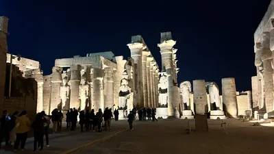 Luxor, Egypt - Feb 9, 2025: Night view of Luxor Temple with illuminated statues and towering hypostyle hall columns, with visitors walking through the ancient complex in Egypt.