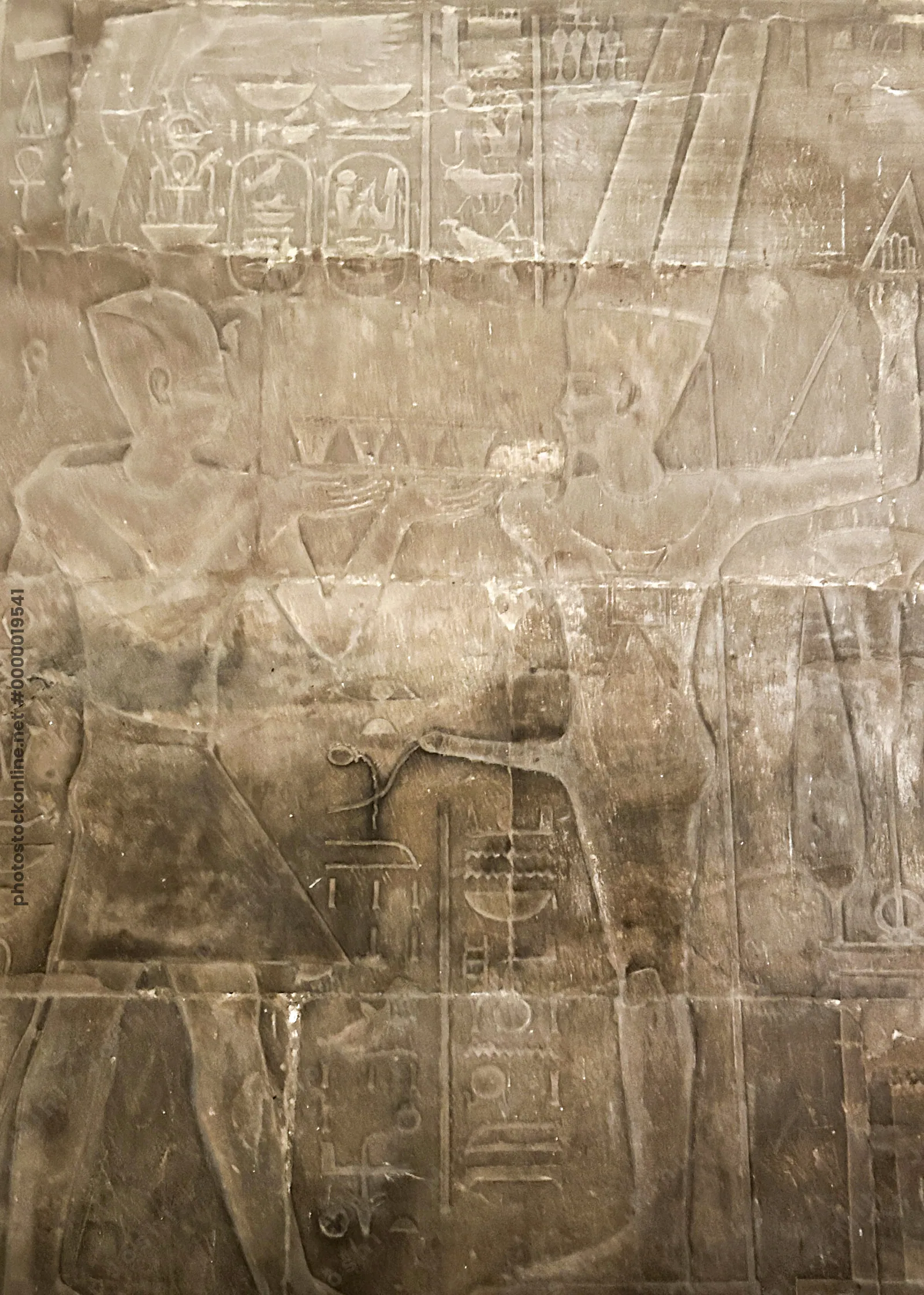 Edfu, Egypt - Feb 9, 2025: Ancient wall relief showing a pharaoh making an offering before Min, the fertility god of ancient Egypt, represented with erect phallus.