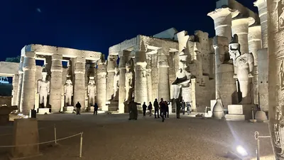 Luxor, Egypt - Feb 9, 2025: Night view of the illuminated colonnade and colossal statues of Luxor Temple in Egypt, with visitors exploring the ancient site.