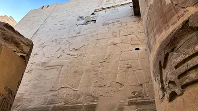 Luxor, Egypt - Feb 10, 2025: Ancient sandstone wall with carved reliefs showing a pharaoh and Egyptian deities inside Karnak Temple in Luxor, Egypt.
