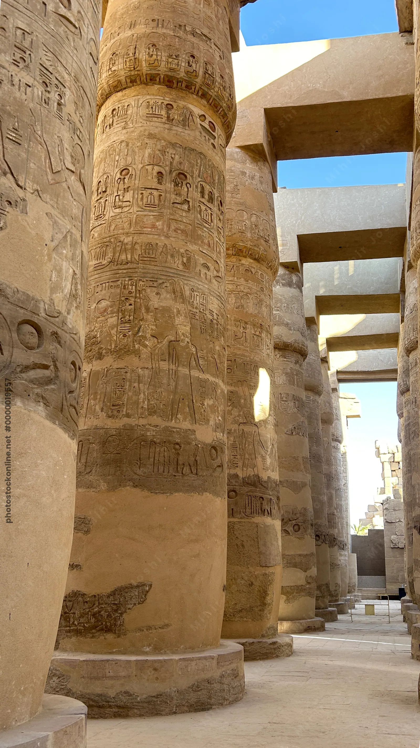 Luxor, Egypt - Feb 10, 2025: Massive sandstone columns decorated with hieroglyphs and reliefs in the Hypostyle Hall of Karnak Temple in Luxor, Egypt.