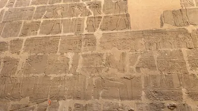 Luxor, Egypt - Feb 10, 2025: Ancient sandstone wall covered with relief carvings and hieroglyphic inscriptions inside the Karnak Temple complex in Luxor, Egypt.