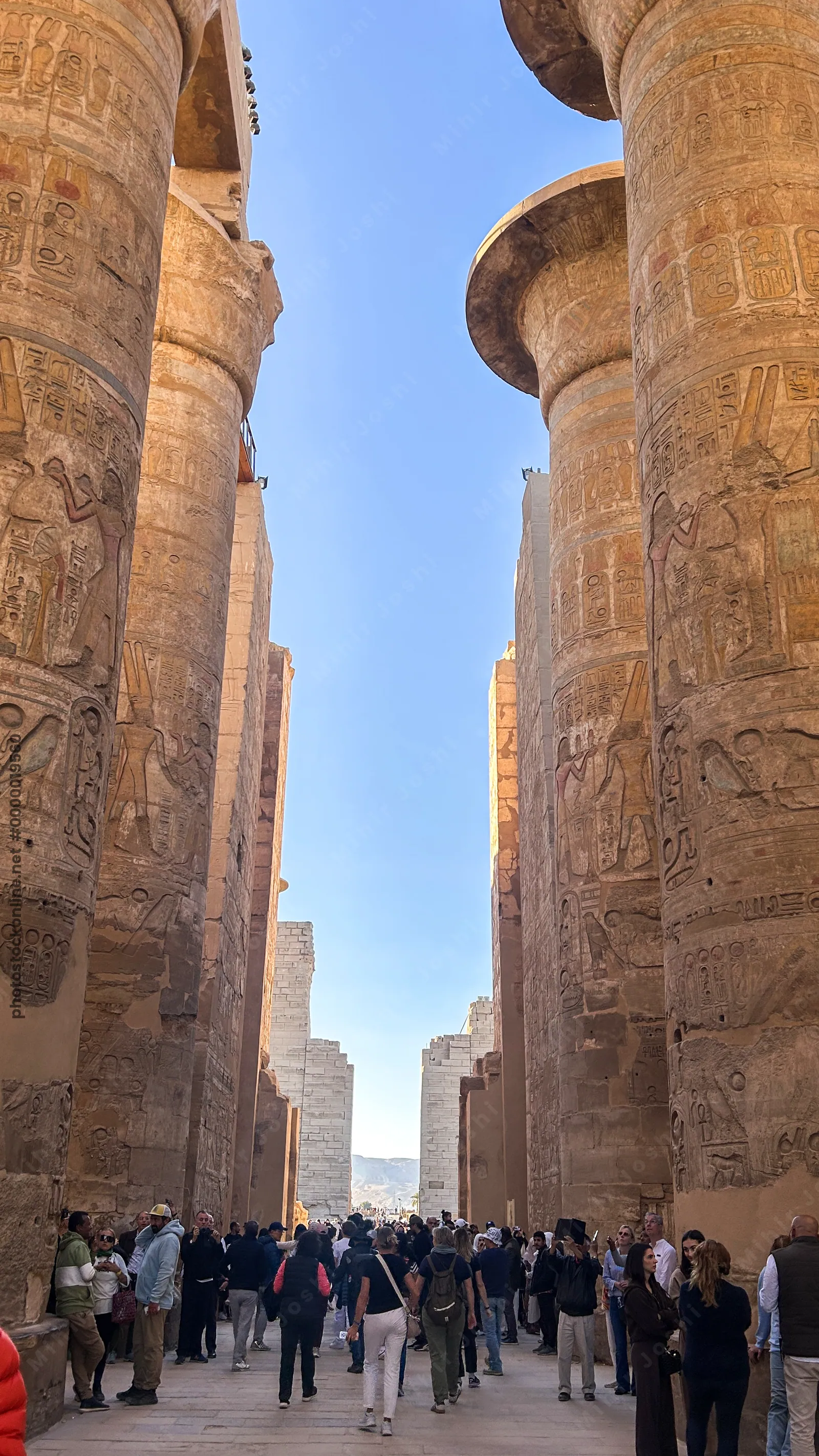Karnak Temple, Luxor, Egypt - Feb 10, 2025: Visitors walk among massive sandstone columns with hieroglyphics inside the Great Hypostyle Hall.