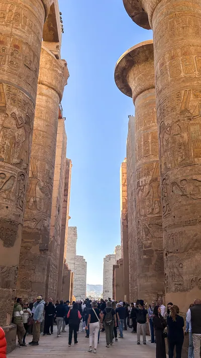 Karnak Temple, Luxor, Egypt - Feb 10, 2025: Visitors walk among massive sandstone columns with hieroglyphics inside the Great Hypostyle Hall.