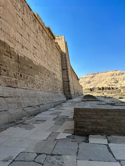 Luxor, Egypt - Feb 11, 2025: Ancient outer wall of Medinet Habu, the Mortuary Temple of Ramesses III, decorated with hieroglyphs and reliefs, located on the west bank of Luxor, Egypt.