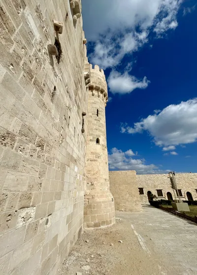 Alexandria, Egypt - Feb 13, 2025: Detailed view of fortified stone wall and tower of the medieval Citadel of Qaitbay fortress.