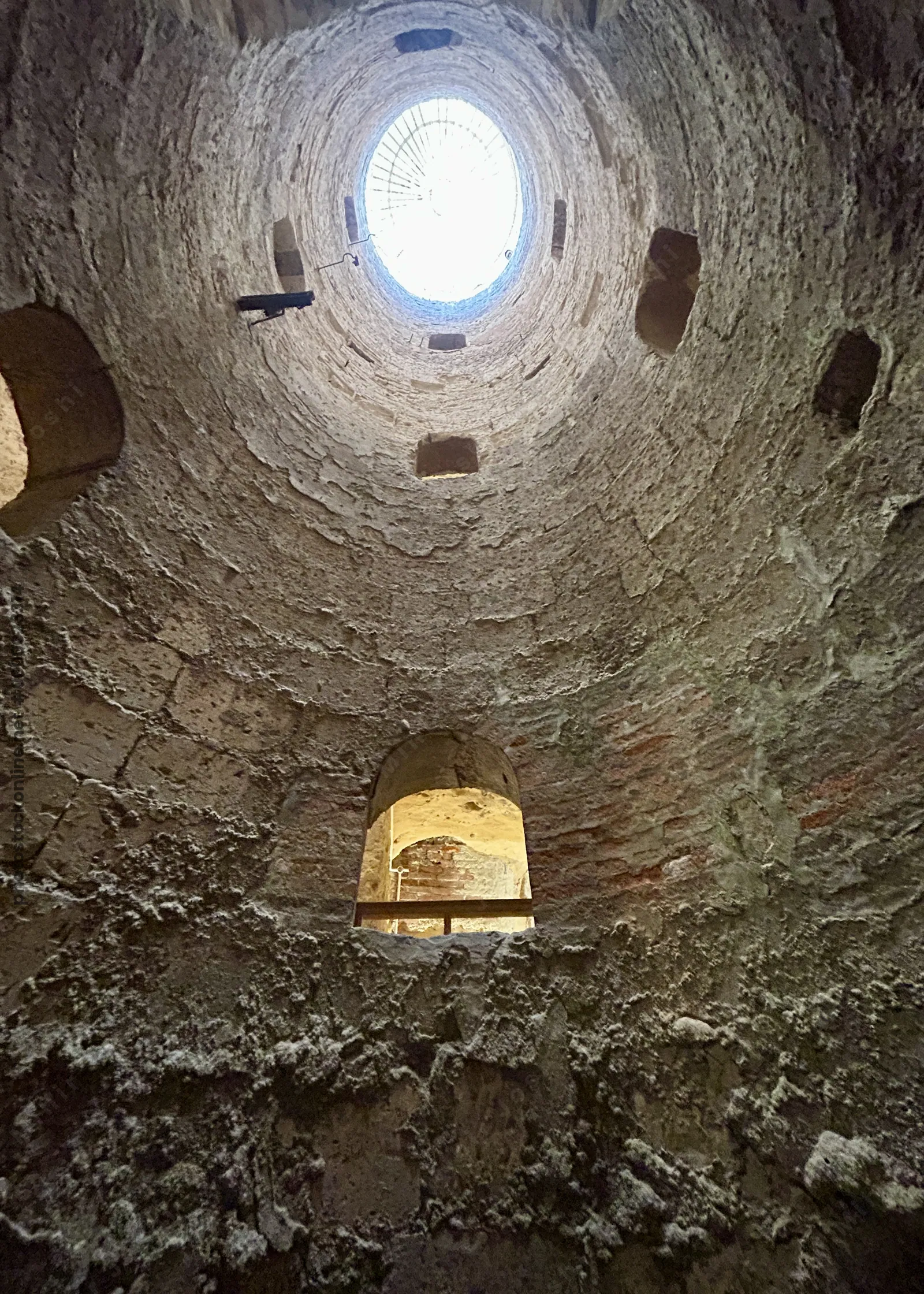 Alexandria, Egypt - Feb 13, 2025: View looking upward through a circular shaft with stone walls at the Catacombs of Kom El Shoqafa, a Greco-Roman necr