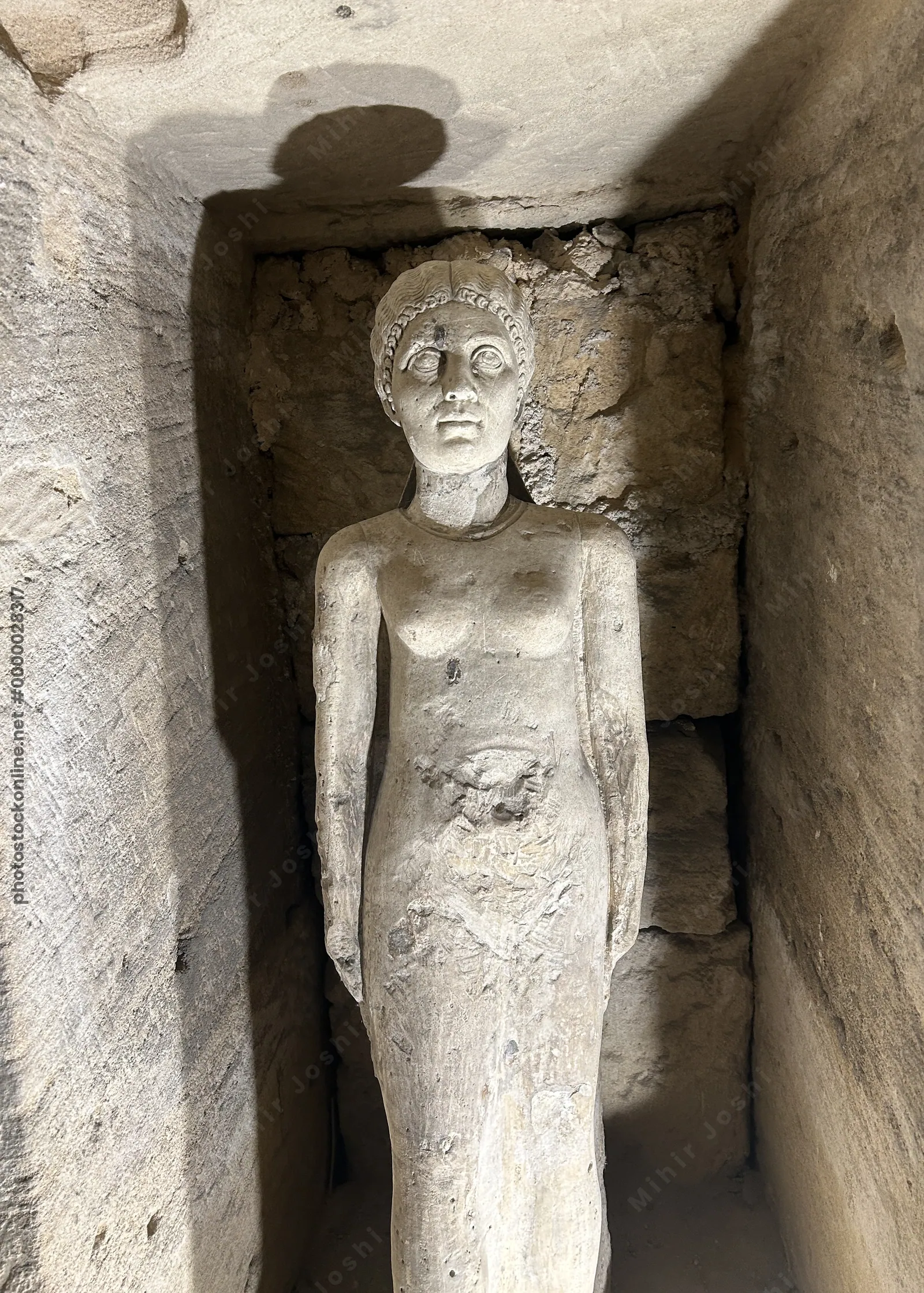Alexandria, Egypt - Feb 13, 2025: Weathered stone statue of a female figure inside the Catacombs of Kom El Shoqafa, a Greco-Roman necropolis and archa