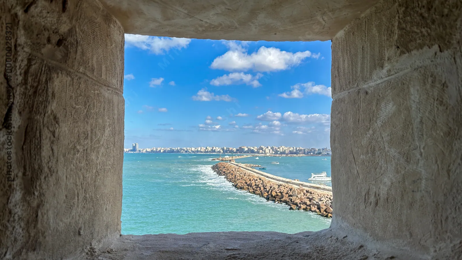 Alexandria, Egypt - Feb 13, 2025: View of the Mediterranean Sea and Alexandria city skyline framed through a stone window opening at the historic Cita