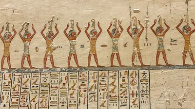 Luxor, Egypt - Feb 2025: Wall relief in the Valley of the Kings depicting a procession of figures performing ritual gestures with hieroglyphic inscrip