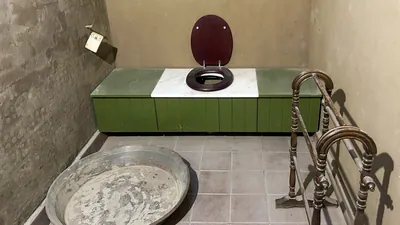 Luxor, Egypt - Feb 11, 2025: Historic bathroom interior at Howard Carter House, with old wooden toilet seat, basin, and towel rack