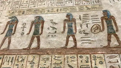 Luxor, Egypt - Feb 11, 2025: Ancient painted wall relief depicting a procession of deities, including a jackal-headed figure, with hieroglyphic inscri