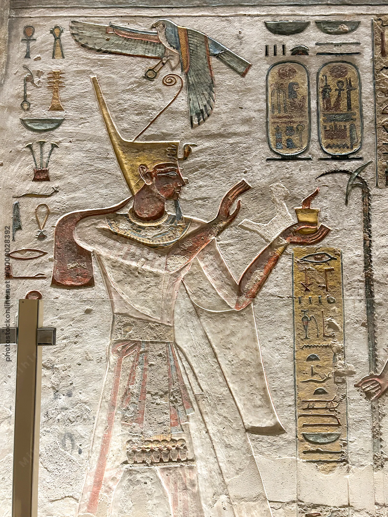 Luxor, Egypt - Feb 11, 2025: Ancient painted wall relief of Ramesses III wearing the tall crown and presenting an offering, with hieroglyphs and carto