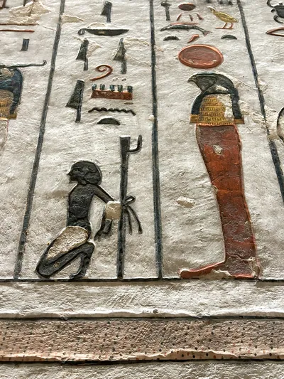 Luxor, Egypt - Feb 11, 2025: painted wall relief from the Tomb of Ramesses III depicting a falcon-headed deity with solar disk and a kneeling captive