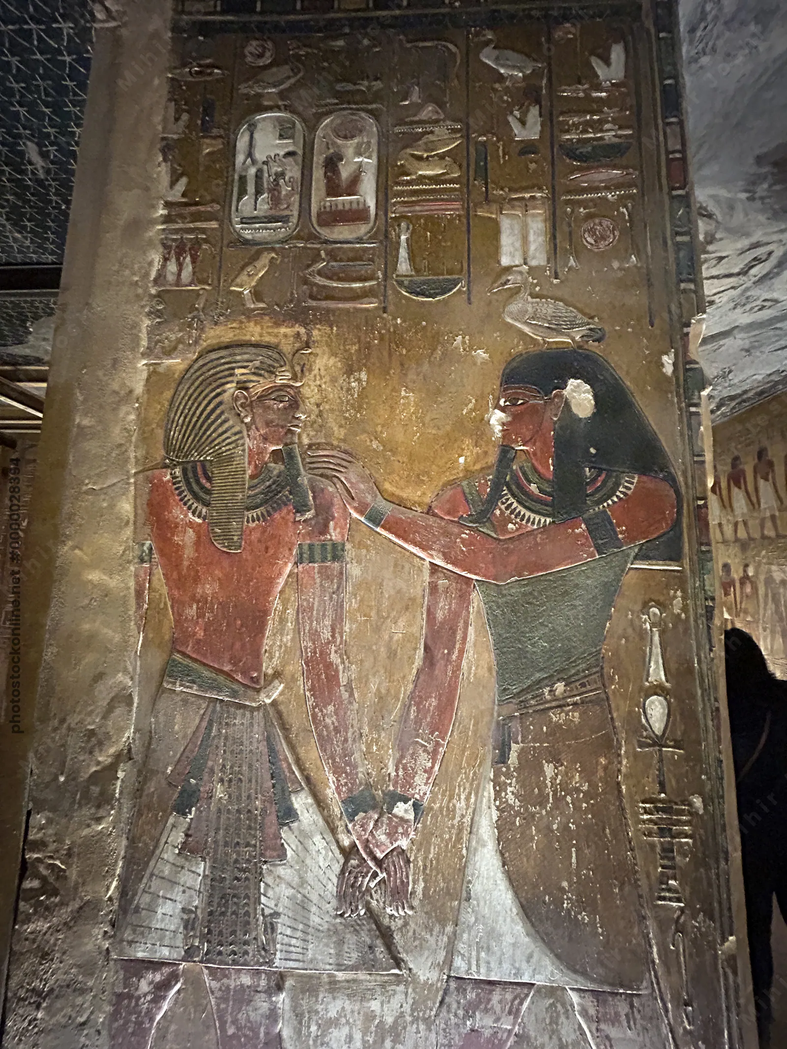 Luxor, Egypt - Feb 11, 2025: Ancient painted wall relief showing the god Geb with a pharaoh, accompanied by hieroglyphs, in a tomb at the Valley of th