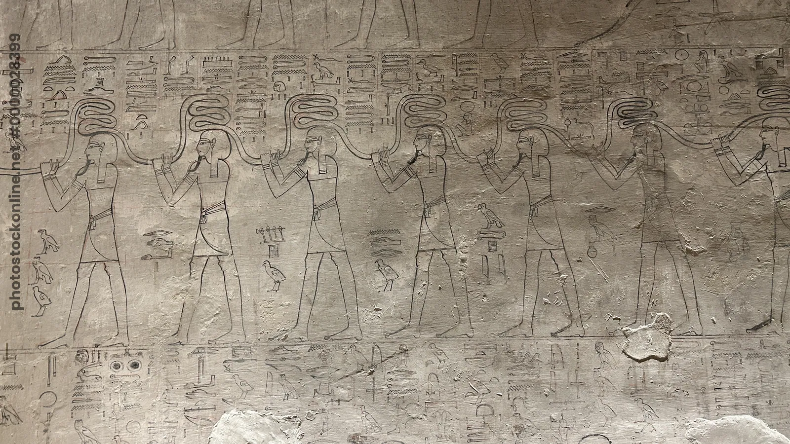 Luxor, Egypt - Feb 11, 2025: Ancient wall relief from side chamber Fa of KV17, the Tomb of Seti I, depicting deities, serpents, and hieroglyphic inscr