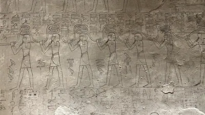 Luxor, Egypt - Feb 11, 2025: Ancient wall relief from side chamber Fa of KV17, the Tomb of Seti I, depicting deities, serpents, and hieroglyphic inscr