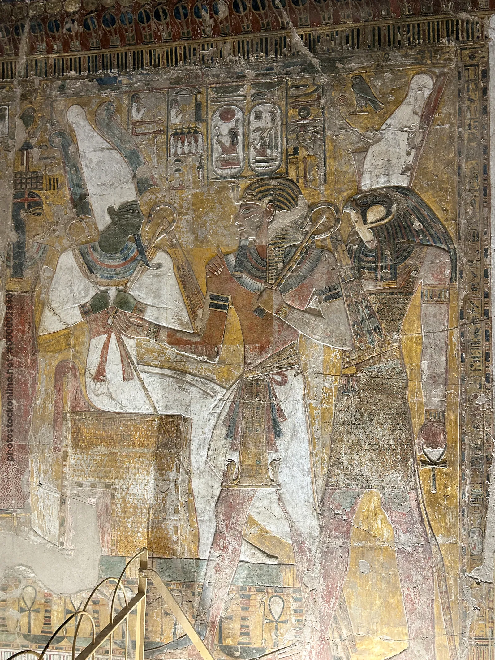 Luxor, Egypt - Feb 11, 2025: Ancient painted wall relief depicting Osiris, Seti I, and Horus inside KV17, the tomb of Seti I, in the Valley of the Kin