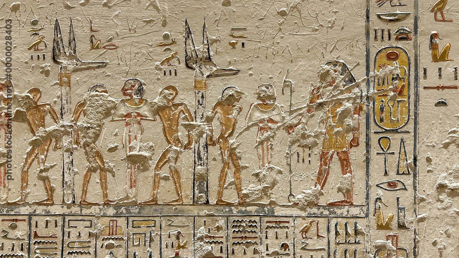 Luxor, Egypt - Feb 11, 2025: Ancient wall relief depicting bound captives flanking Anubis standards with hieroglyphic inscriptions in a tomb at the Va