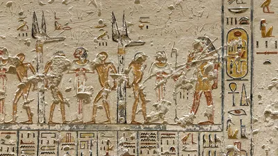 Luxor, Egypt - Feb 11, 2025: Ancient wall relief depicting bound captives flanking Anubis standards with hieroglyphic inscriptions in a tomb at the Va