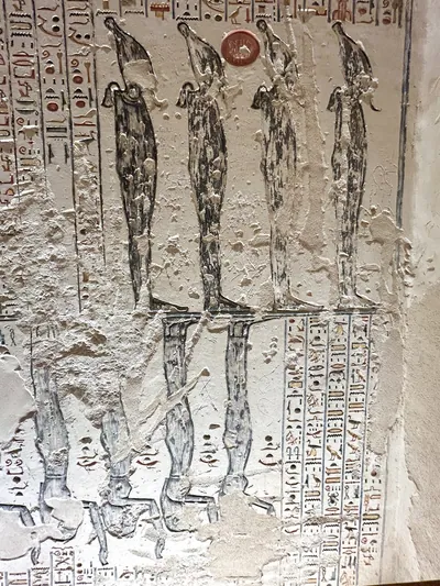 Luxor, Egypt - Feb 11, 2025: Ancient relief depicting multiple standing deities with tall headdresses and hieroglyphic inscriptions in a tomb at the V