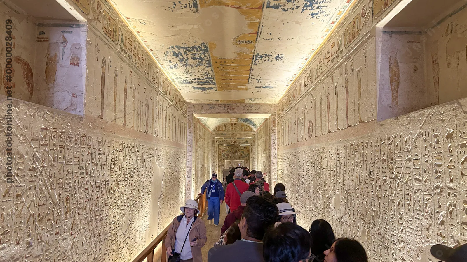 Luxor, Egypt - 11-Feb-2025: Tourists walk through a decorated corridor inside a tomb in the Valley of the Kings, with walls and ceilings covered in an