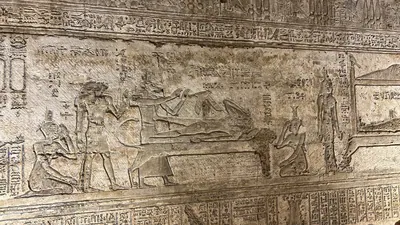 Dendera, Egypt - Feb 10, 2025: Ancient wall relief showing Osiris lying on a bier and Isis in the form of a kite above him, representing the conceptio