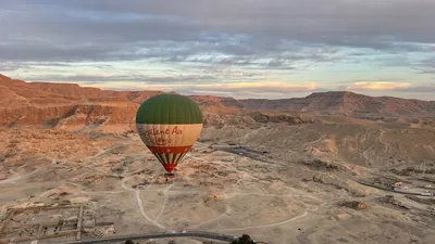 Luxor, Egypt - Feb 10, 2025: Hot air balloon floating above desert mountains and ancient ruins near Luxor, offering a scenic aerial perspective.