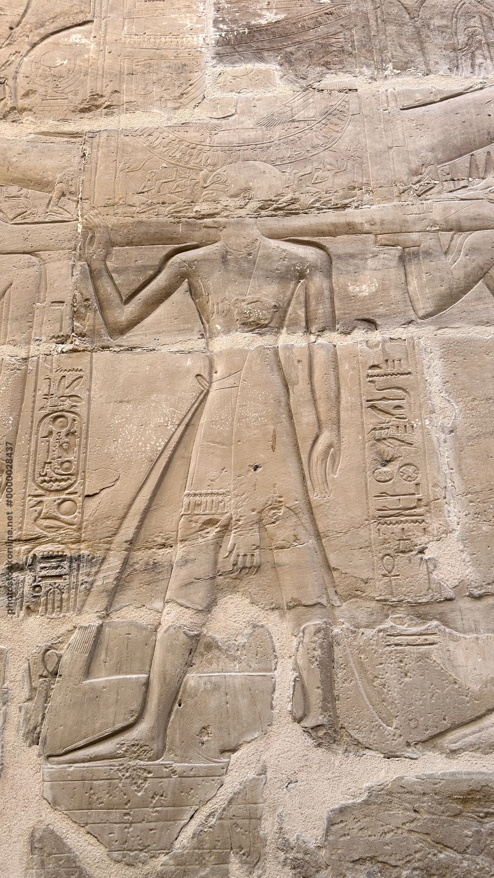 Karnak Temple, Luxor, Egypt - Feb 10, 2025: Detailed stone relief of a standing human figure with surrounding hieroglyphics on the walls of Karnak Tem