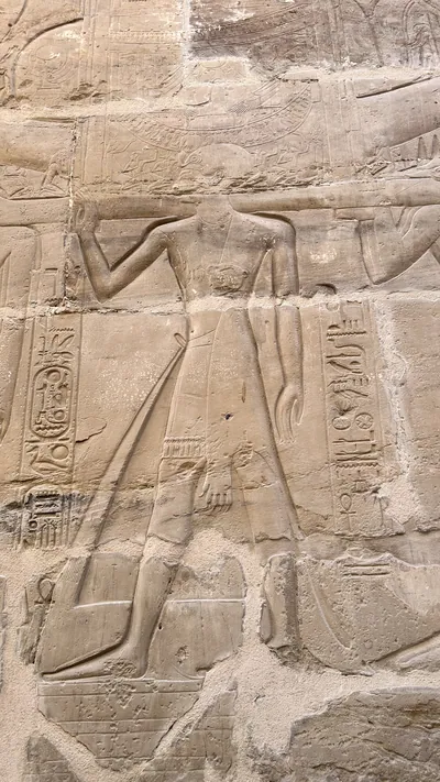 Karnak Temple, Luxor, Egypt - Feb 10, 2025: Detailed stone relief of a standing human figure with surrounding hieroglyphics on the walls of Karnak Tem