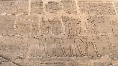 Luxor, Egypt - Feb 10, 2025: Ancient sandstone relief depicting Egyptian gods standing on a sacred ceremonial barque at Karnak Temple in Luxor, Egypt.