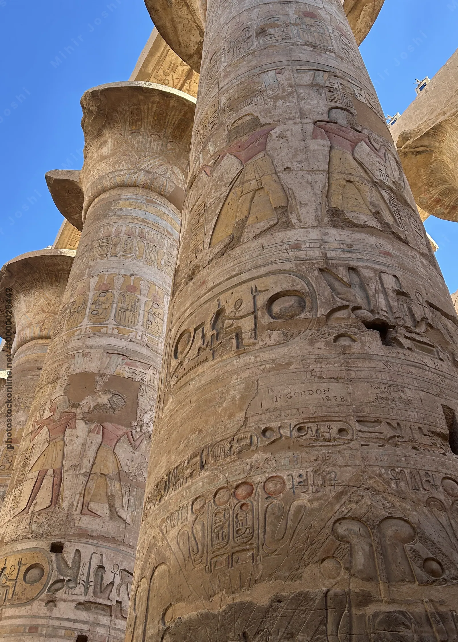 Luxor, Egypt - Feb 10, 2025: Massive sandstone columns with painted reliefs and hieroglyphs inside the Hypostyle Hall of Karnak Temple in Luxor, Egypt