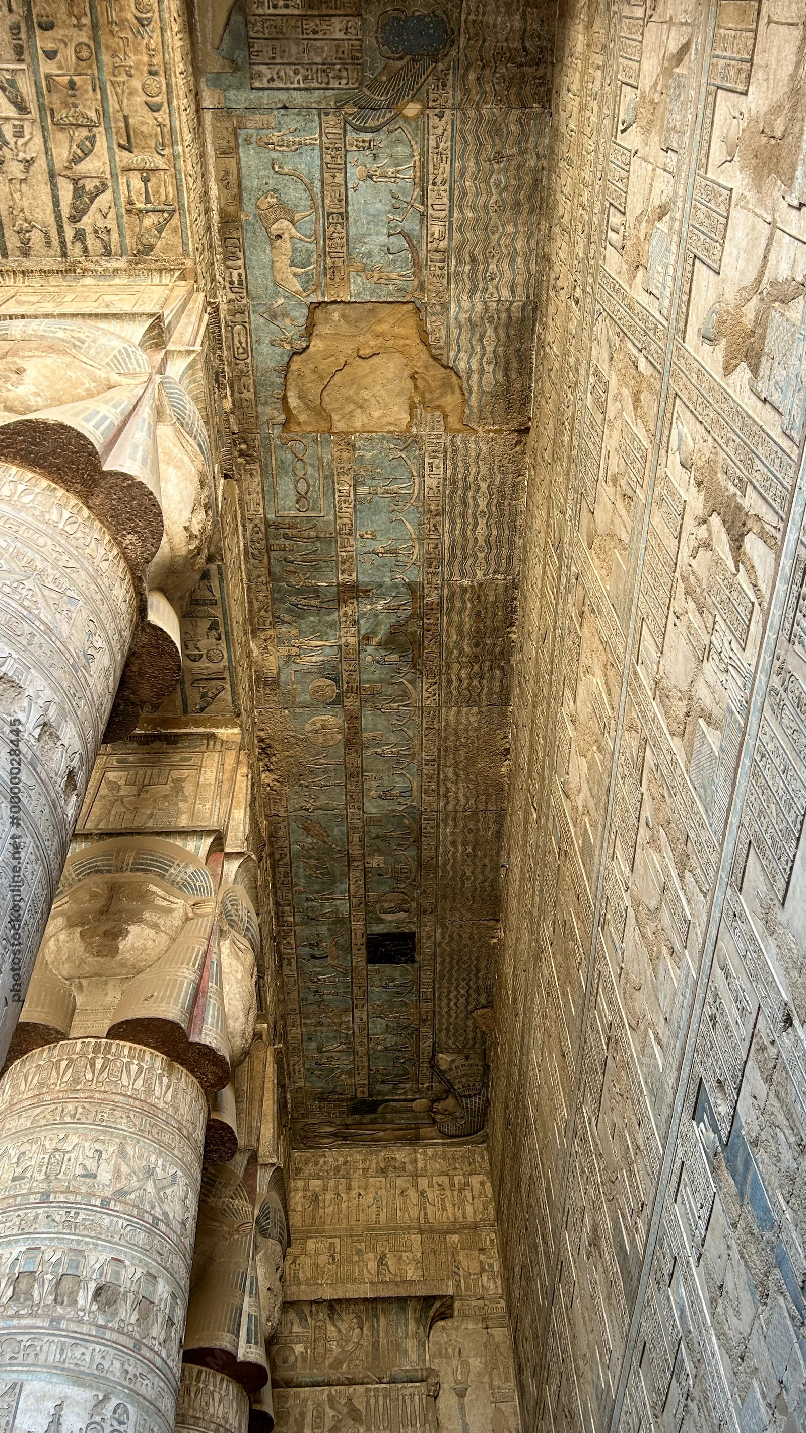 Ancient hieroglyphs and carved columns with painted ceiling details inside Dendera Temple in Egypt.