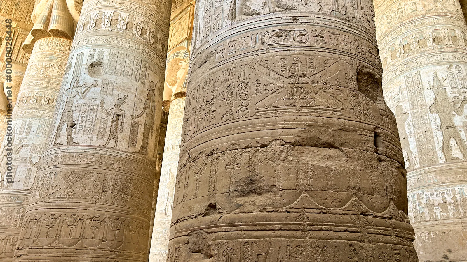 Dendera, Egypt - Feb 10, 2025: Detailed carvings and hieroglyphs on massive stone columns inside the ancient Dendera Temple in Egypt.