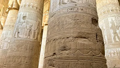 Dendera, Egypt - Feb 10, 2025: Detailed carvings and hieroglyphs on massive stone columns inside the ancient Dendera Temple in Egypt.